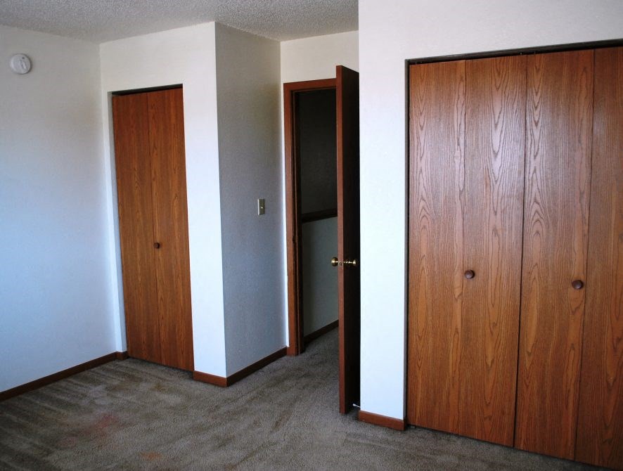 an empty room with two doors and a closet