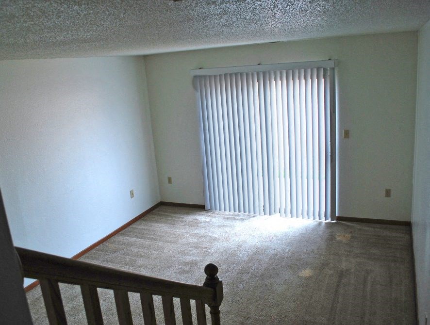 a living room with a large window and a staircase