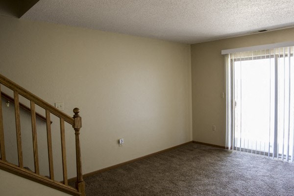 a living room with a staircase and a large window