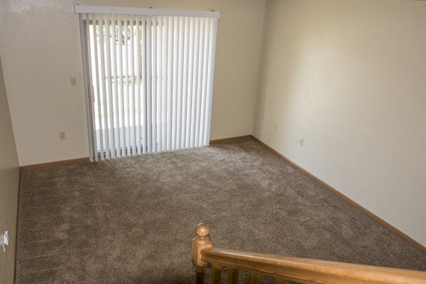 an empty living room with a window and a staircase