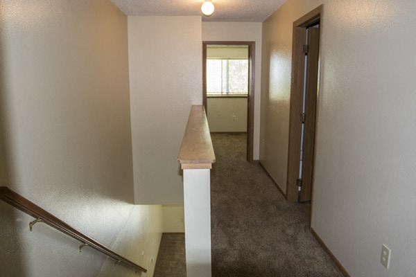 the upstairs hallway of a house with a staircase and a window