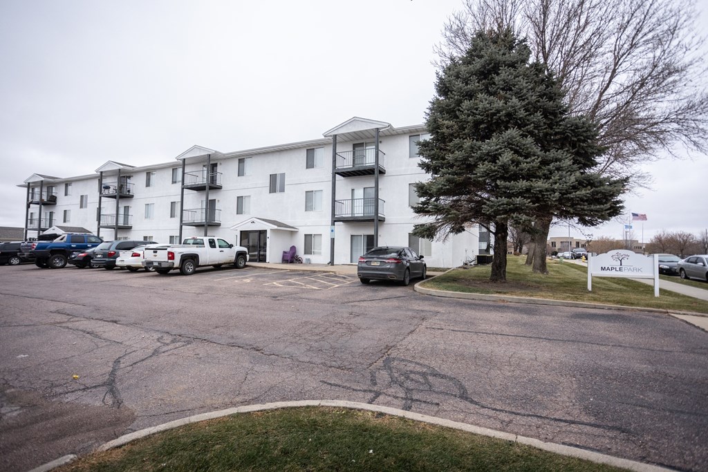 a large white apartment building with cars parked in front of it