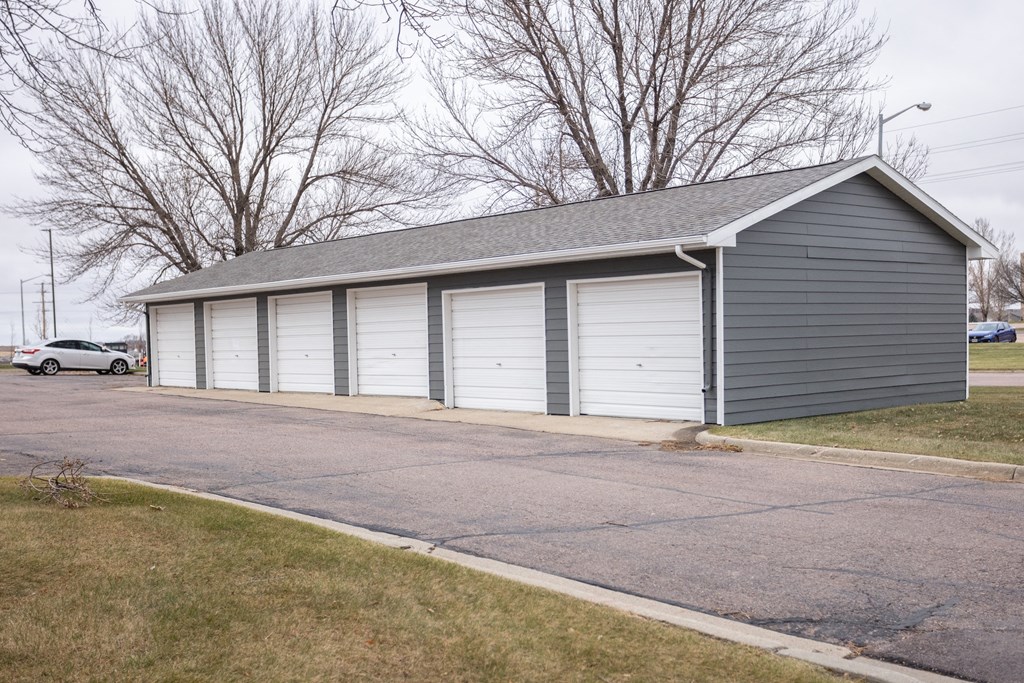 a gray garage with white doors on the side of a street