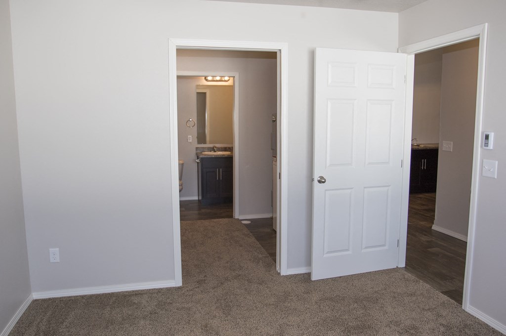 a bedroom with a door open to a hallway and a bathroom