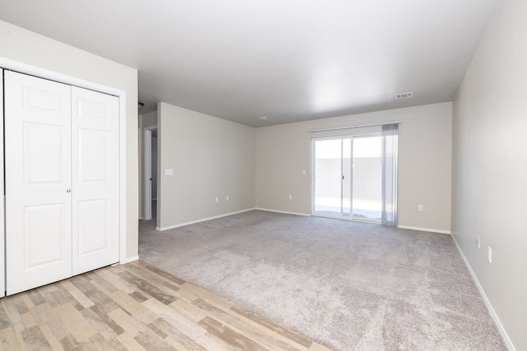 A room with a white door and a carpeted floor.