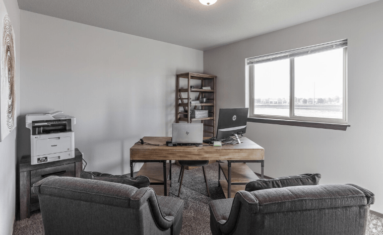 a living room with two couches and a desk with a laptop