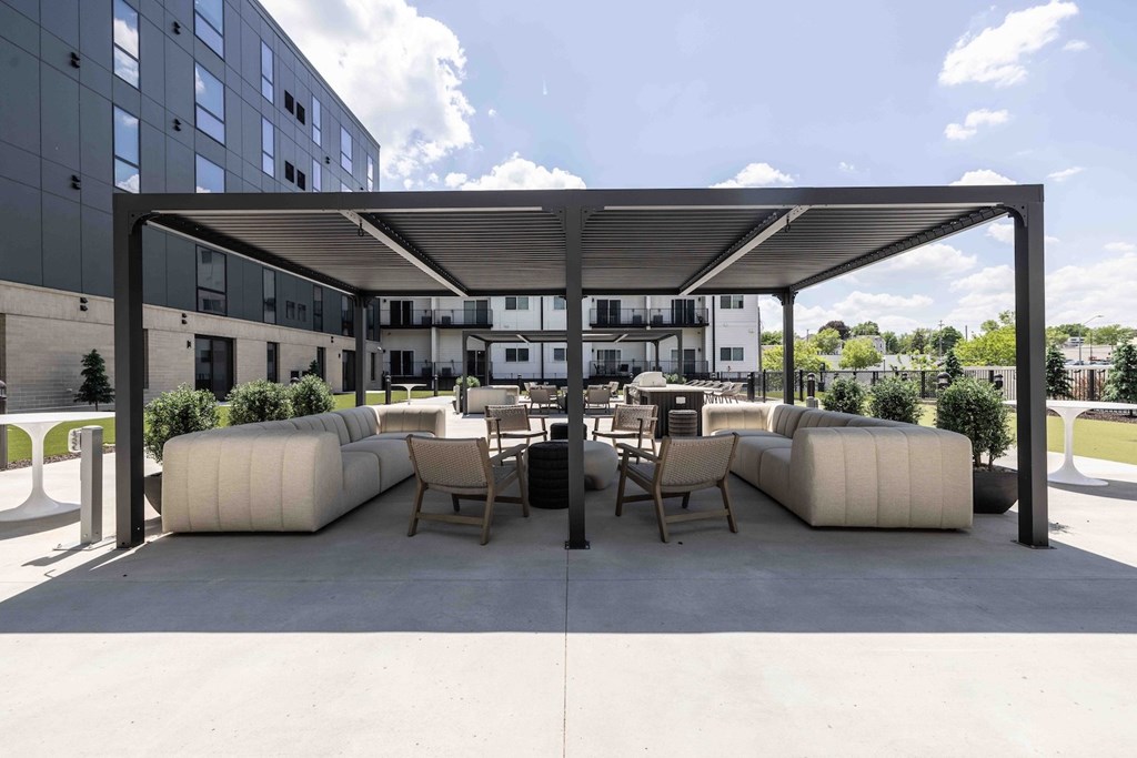 A modern outdoor seating area with white furniture and a black metal structure.