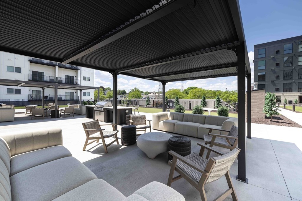 A patio with a black awning and white furniture.
