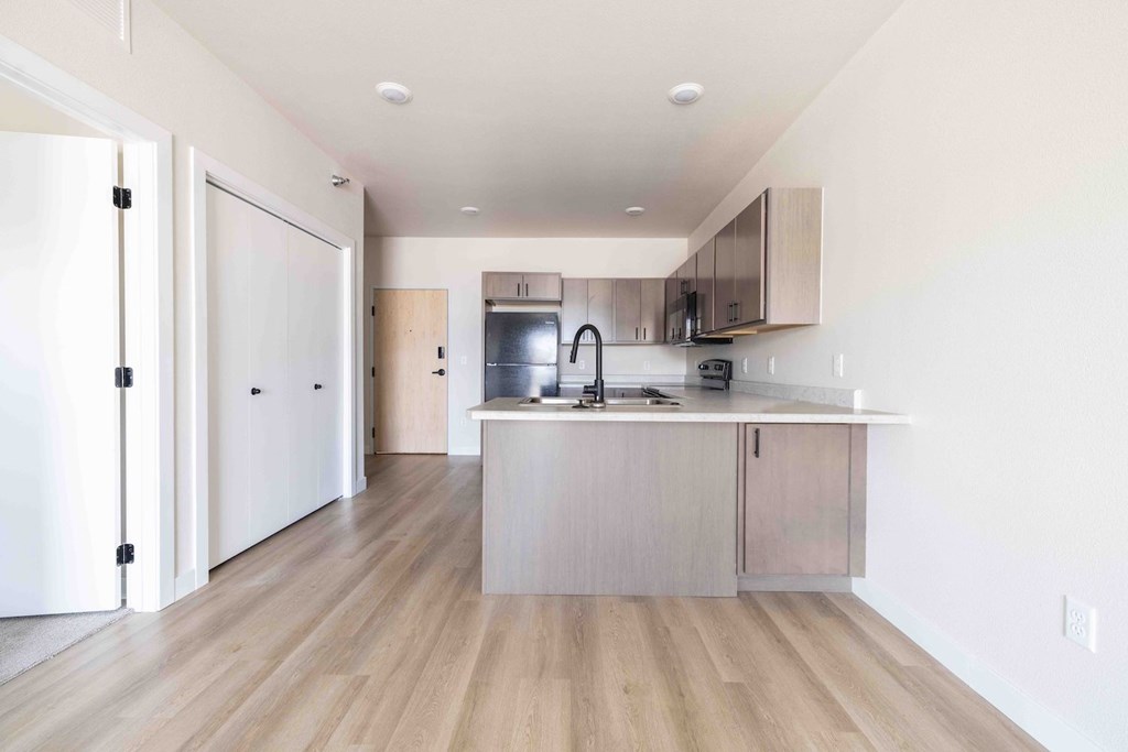 A kitchen with a white fridge and wooden floors.