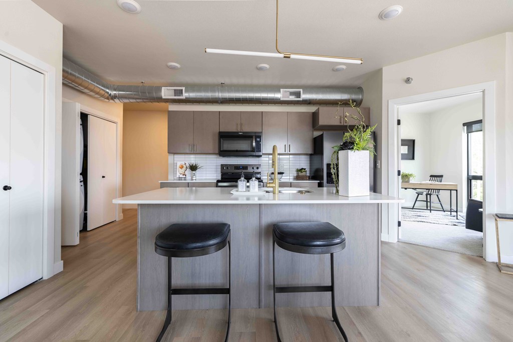 A modern kitchen with a white countertop and two bar stools.