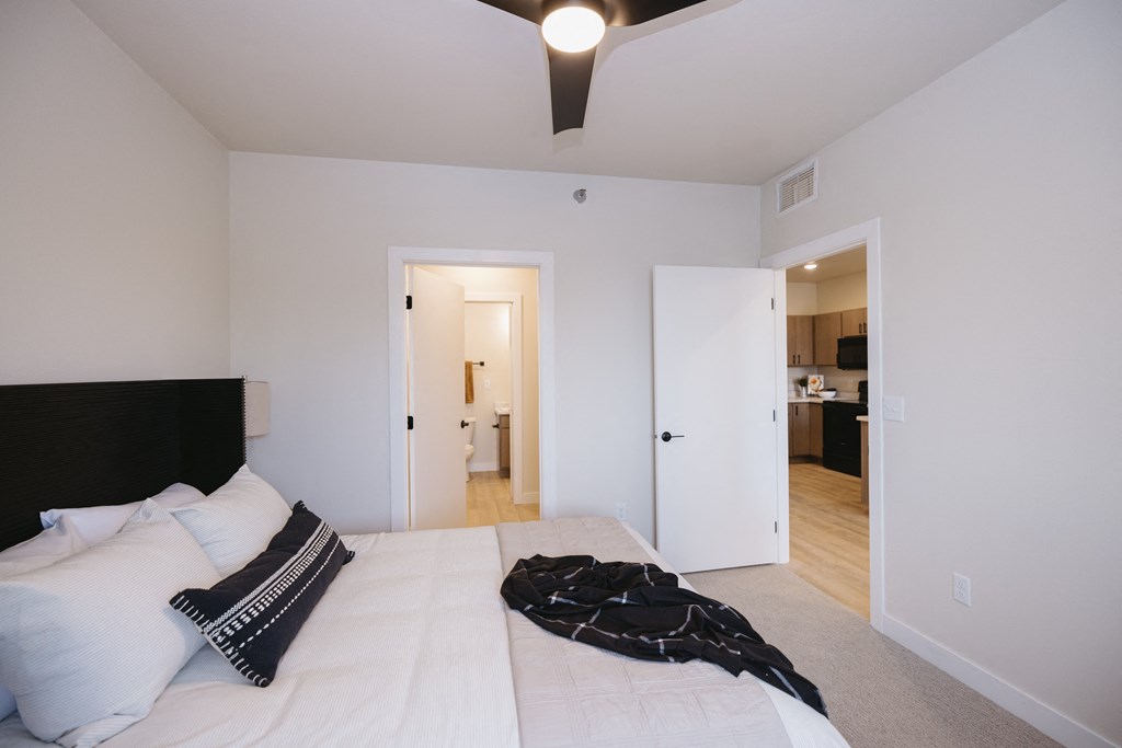 a bedroom with a large white bed and a ceiling fan