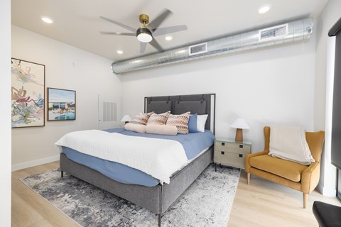 A bedroom with a bed, a chair, and a ceiling fan.