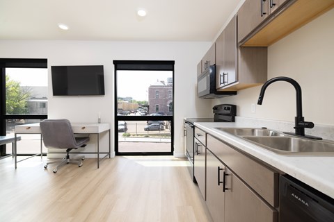 A modern kitchen with a desk and chair in the foreground.