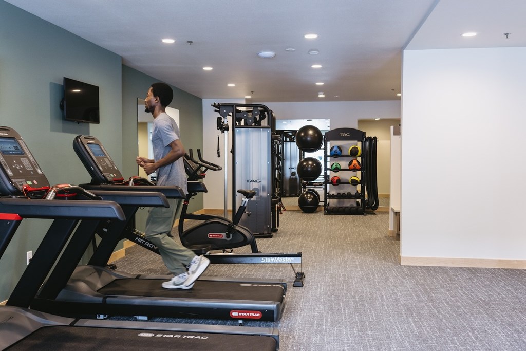 A man is running on a treadmill in a gym.