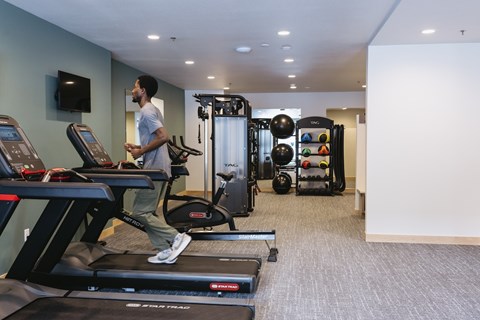 A man is running on a treadmill in a gym.