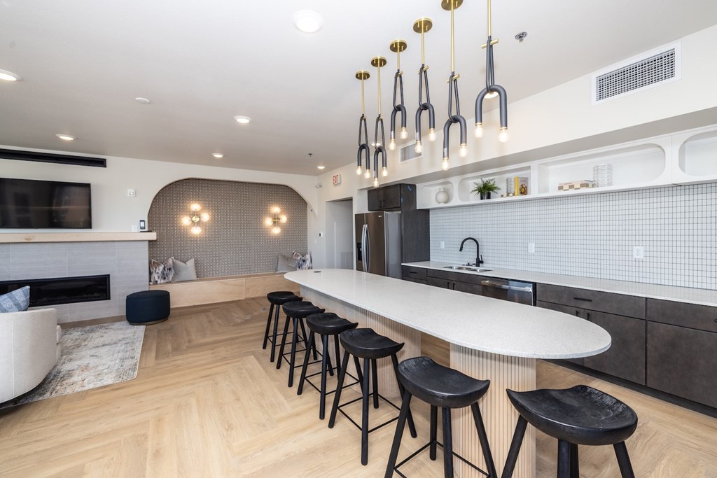 A modern kitchen with a bar area and black stools.