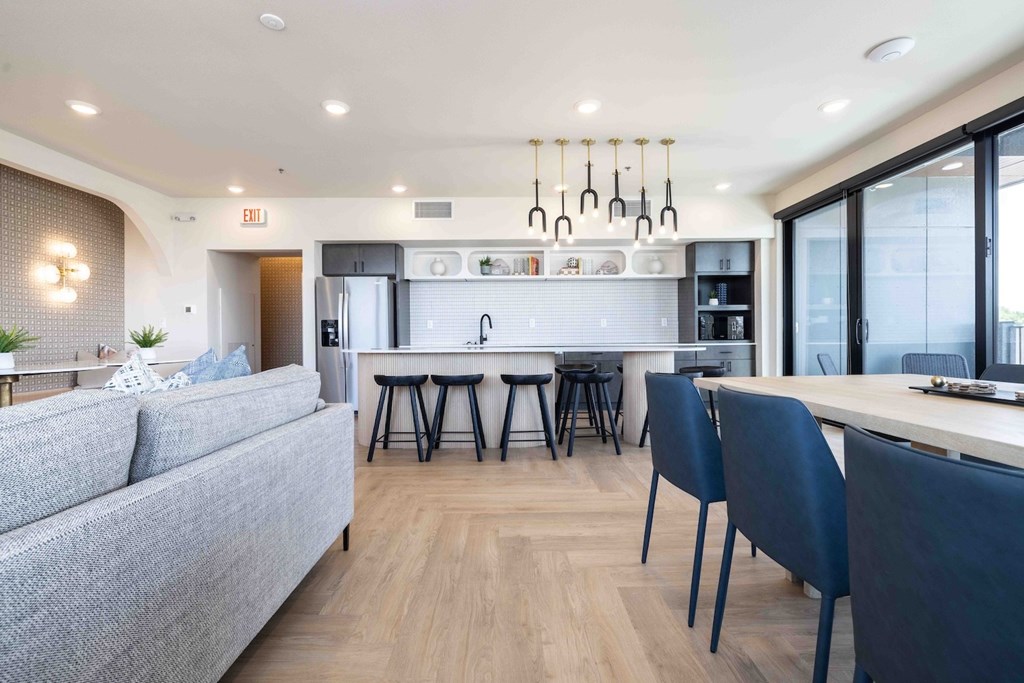 A modern kitchen with a grey couch and black chairs.