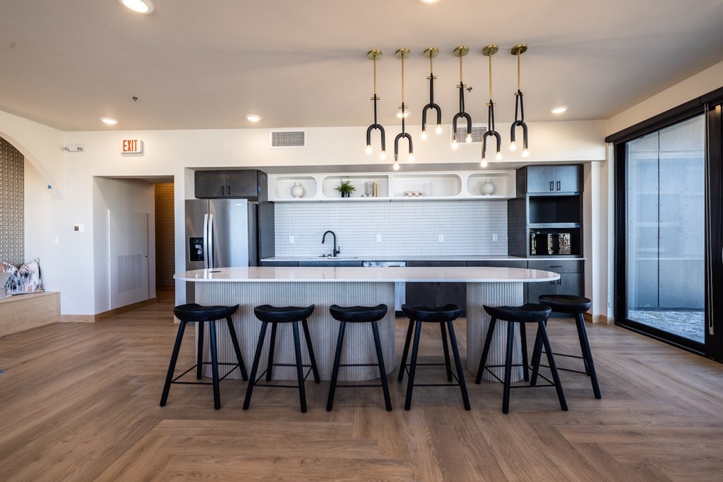 A modern kitchen with a white countertop and black bar stools.