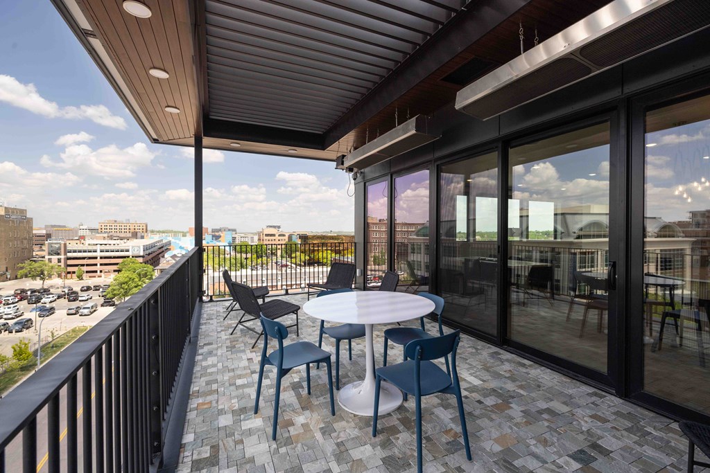 A balcony with a table and chairs overlooking a parking lot.