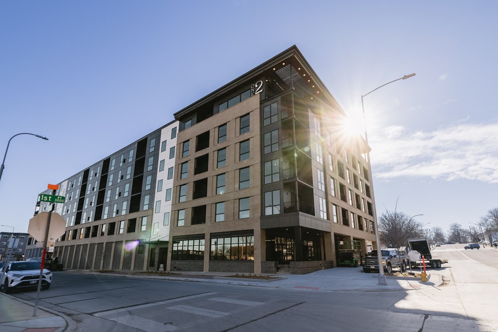 A modern building with a glass facade is bathed in sunlight.