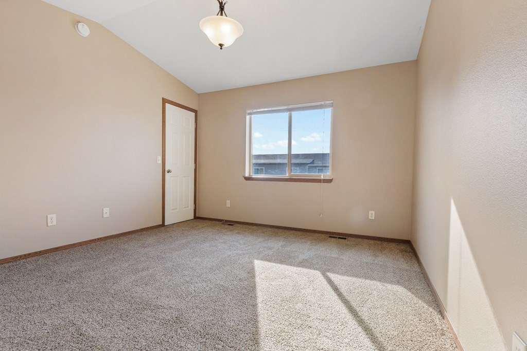 A room with a carpeted floor, a window, and a door.
