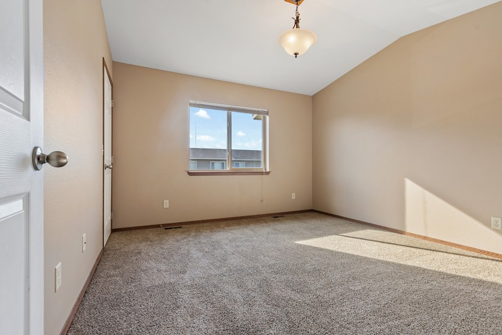 A room with a carpeted floor, a window, and a door.