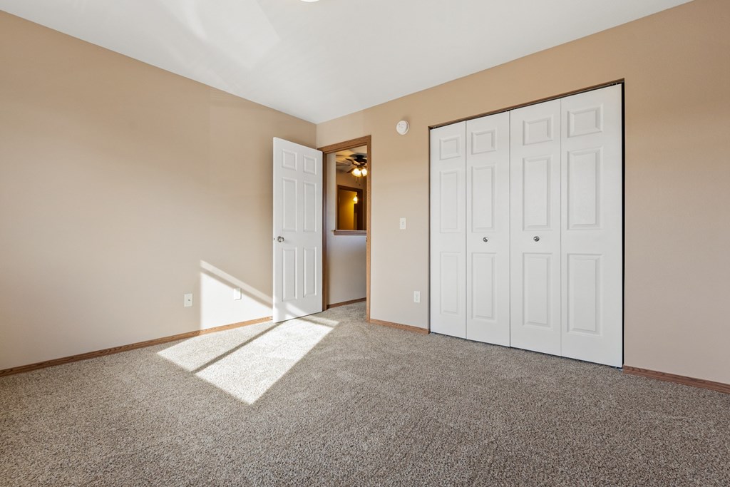 A room with a carpeted floor and two white doors.