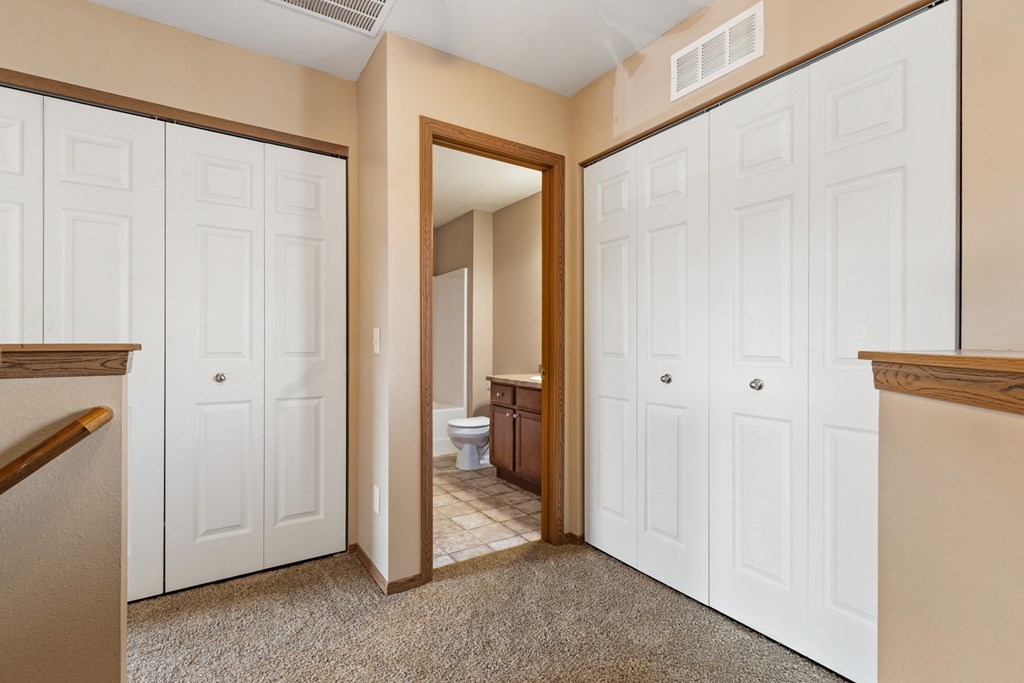 A hallway with white doors and a carpeted floor.