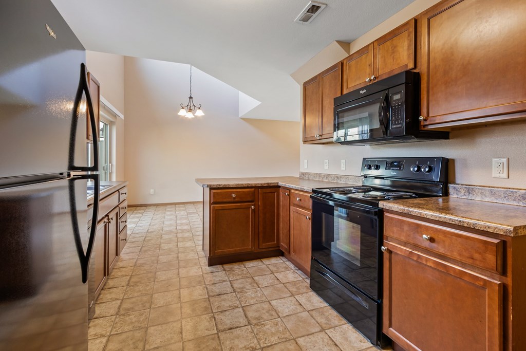 A kitchen with black appliances and wooden cabinets.