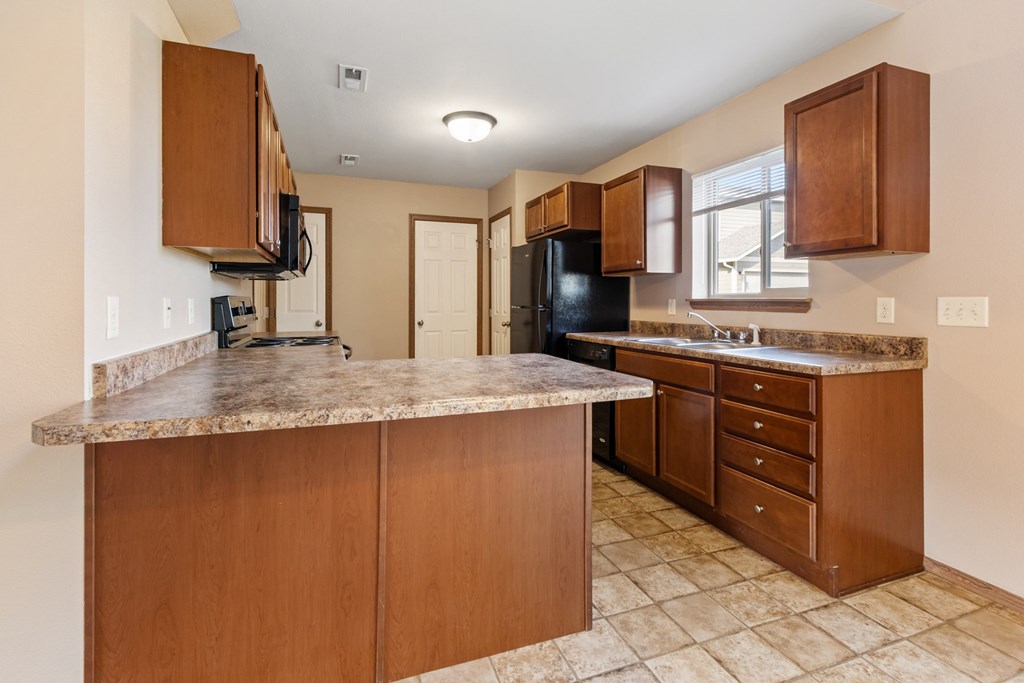 A kitchen with brown cabinets and a granite counter top.
