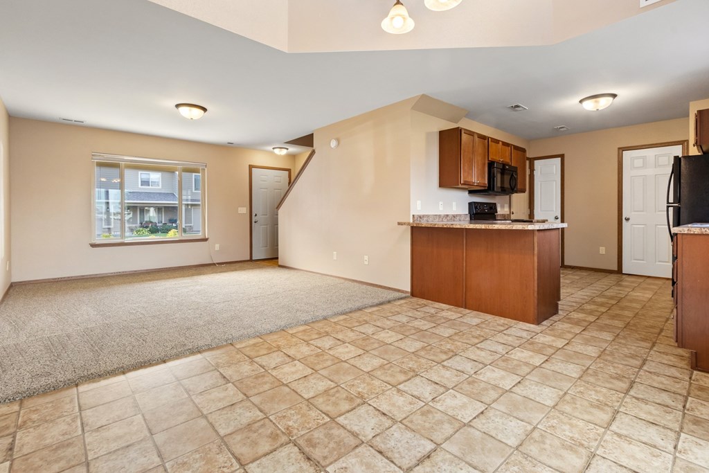A spacious living room with a kitchen area in the background.
