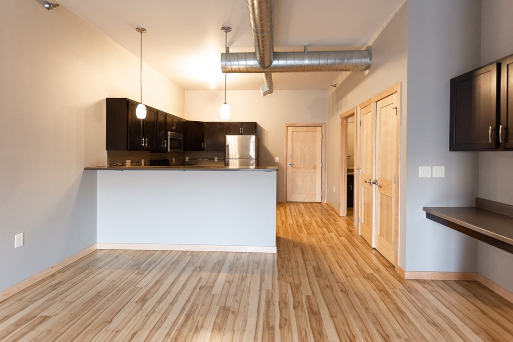 a kitchen and living room with wood flooring and a white counter top in a