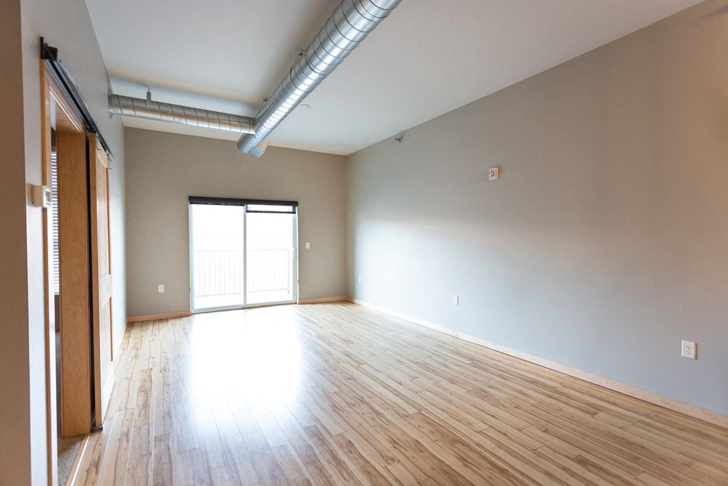an empty living room with wood floors and a door to a garage