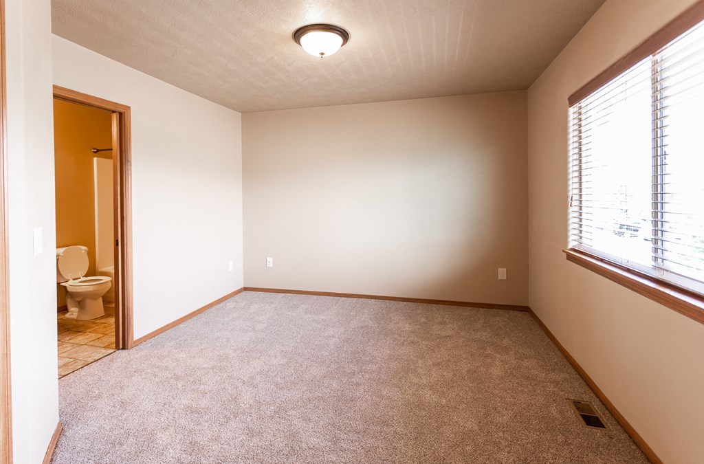 an empty living room with a toilet and a window