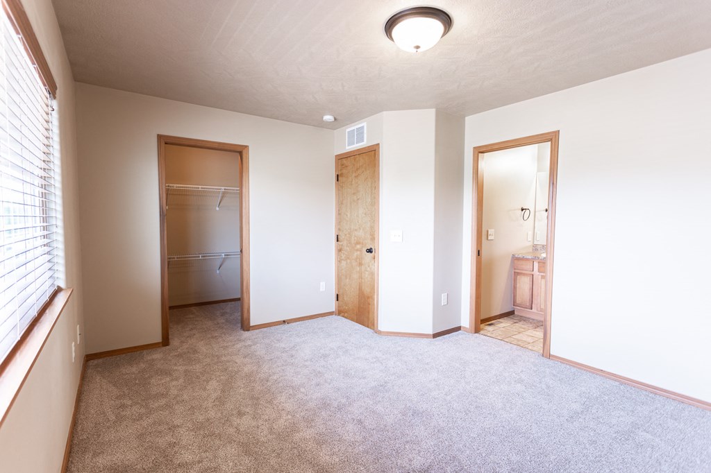 an empty room with a door to a bathroom and a closet