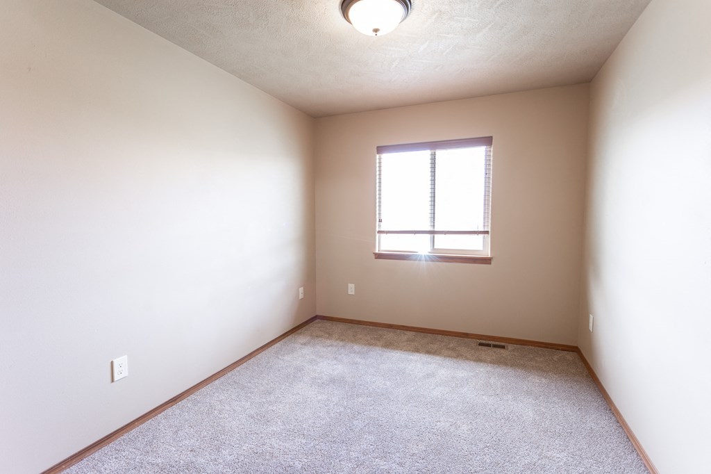 an empty room with a window and carpet