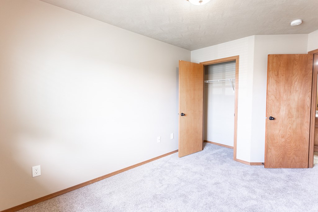 an empty room with a closet and a door to a bathroom