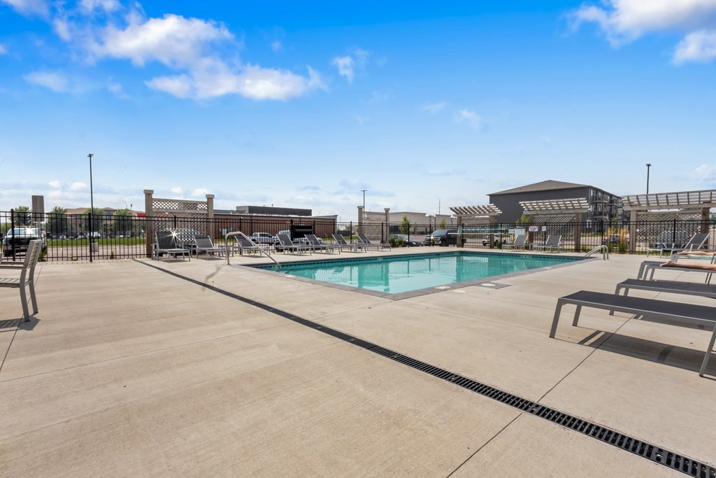 A large outdoor swimming pool with a concrete deck and a building in the background.