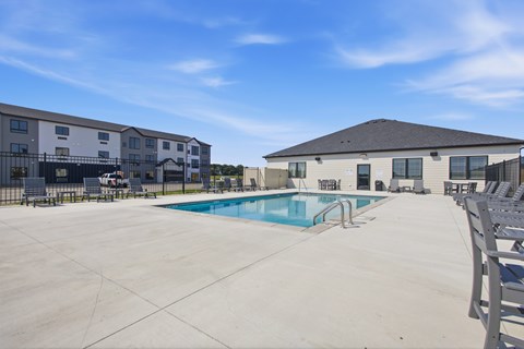 A large outdoor swimming pool with a slide and lounge chairs in front of a building.