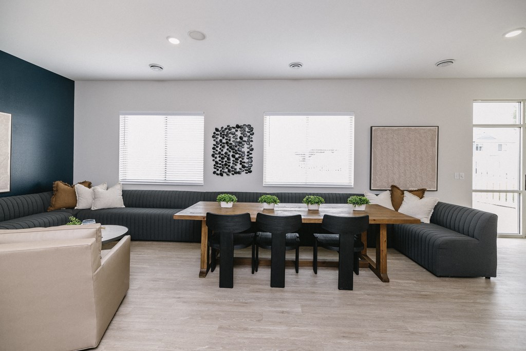 a living and dining room with black couches and a wooden table