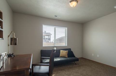 an empty living room with a couch and a desk
