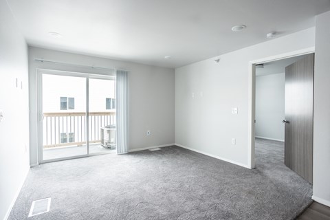 an empty living room with a door to a balcony