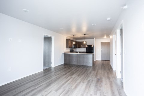an empty living room and kitchen with white walls and wood floors