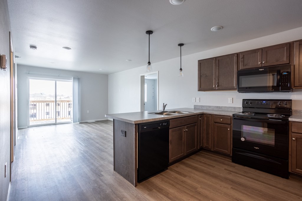 an empty kitchen and living room with wooden floors and wooden cabinets