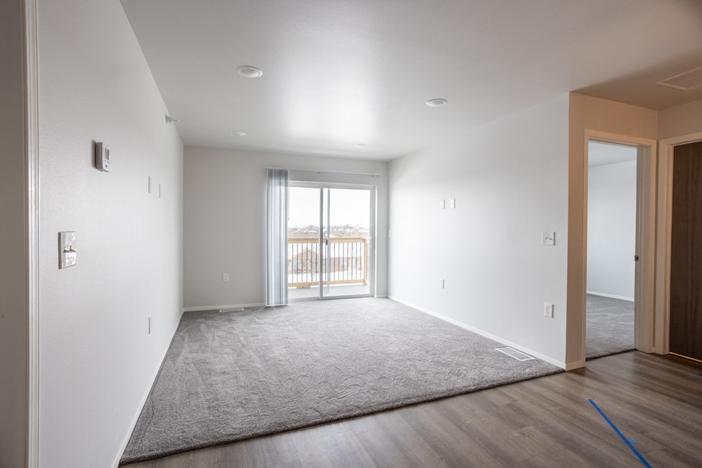 an empty living room with a door to a balcony