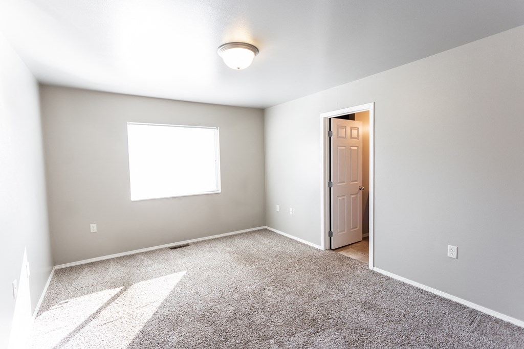 an empty room with a door to a closet and a window