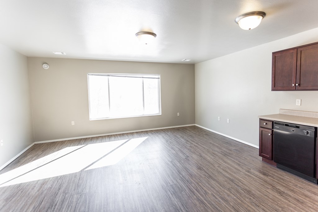 an empty kitchen and living room with wood flooring and a window