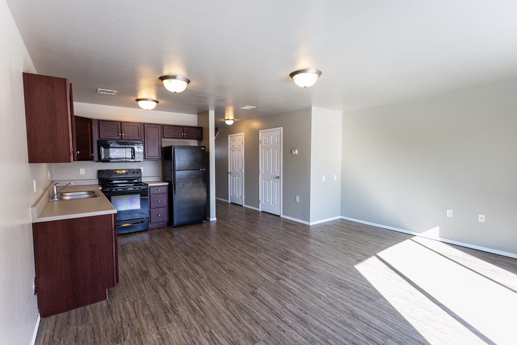 a kitchen and living room with wood flooring in an empty apartment