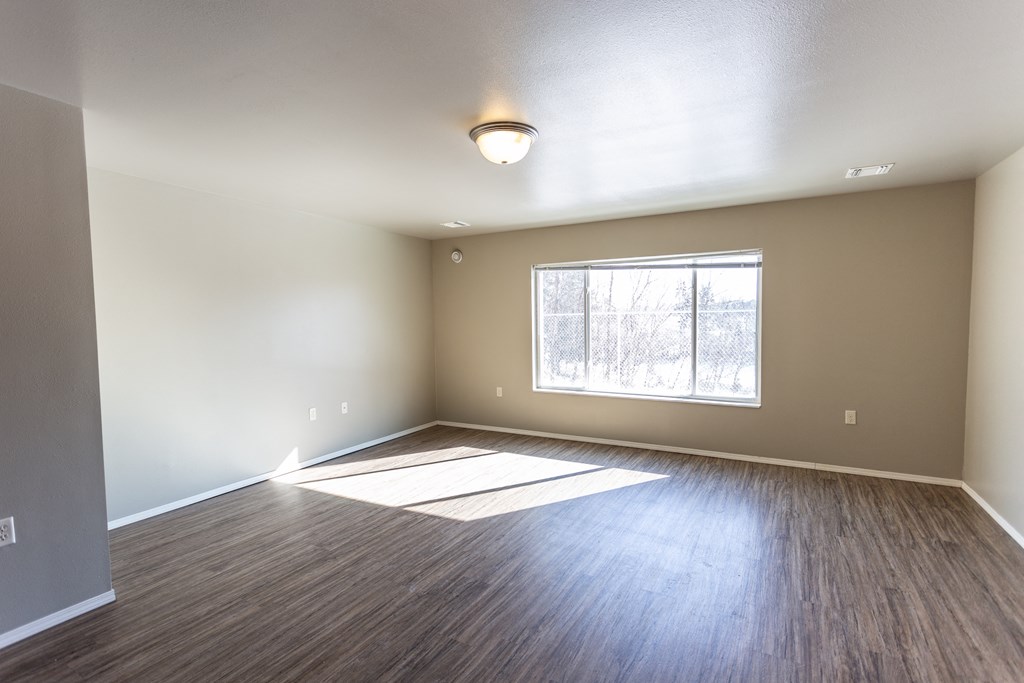 an empty living room with wood floors and a window