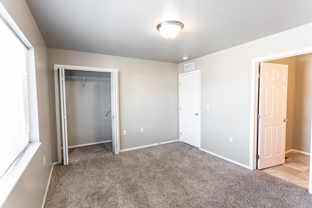 an empty room with a door to a closet and a window